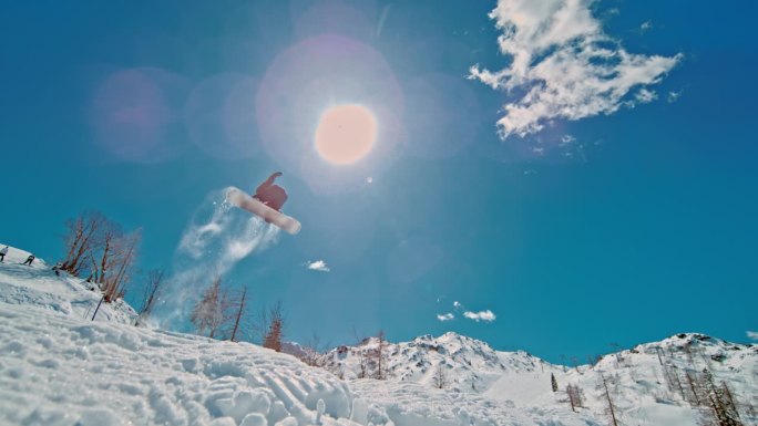 滑雪者享受假期的慢镜头。男在雪山上玩滑雪板。他在练习特技。