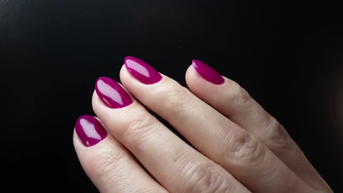 一位女士展示用亮紫色指甲油涂的指甲