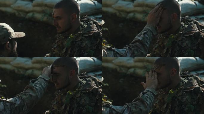 一个士兵在他同伴的脸上抹泥巴