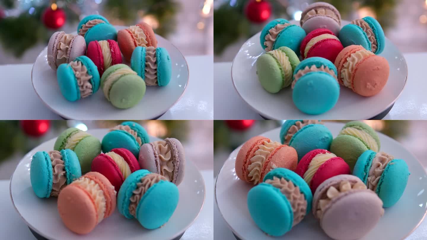 碟子上以圣诞树为背景的甜点马卡龙，红色、蓝色、绿色、粉红色和橙色，由杏仁粉和奶油制成的法式糕点，美味
