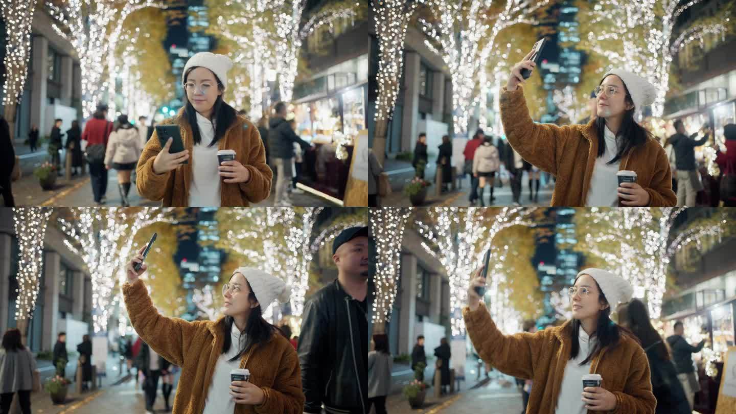 一名兴奋开朗的女子用她的手机拍下了圣诞主题城市的美丽灯光。