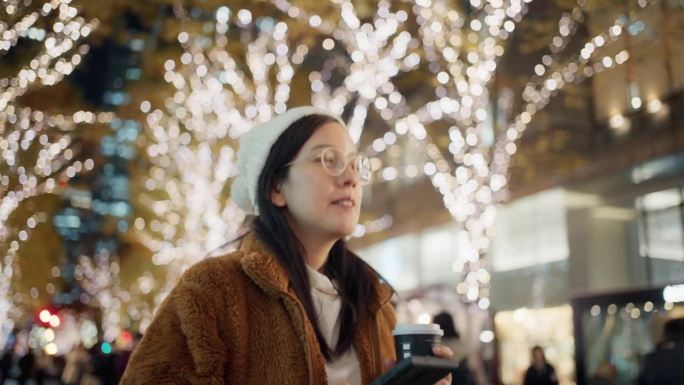 快乐的游客们用手机拍下圣诞节期间被装饰和点亮的城市街道。