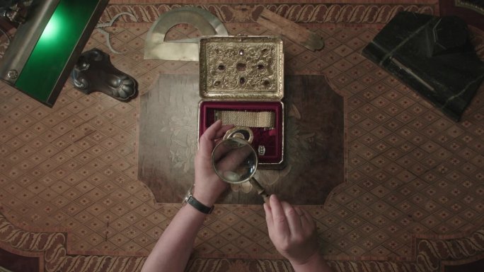 铜制首饰盒，桌上放着宝石，配有放大镜