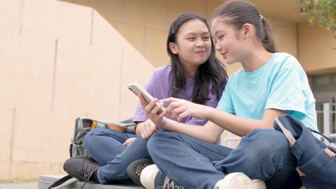 快乐的亚洲女生在学校使用智能手机