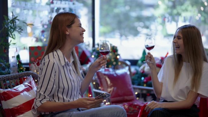 两个美女碰杯聊天，畅饮红酒，一起庆祝。