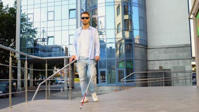 一个年轻的盲人拄着拐杖走在街上