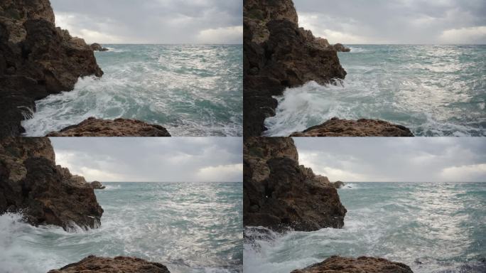 海上阴天，高崖被海浪冲击，分裂成许多小水滴。慢动作。