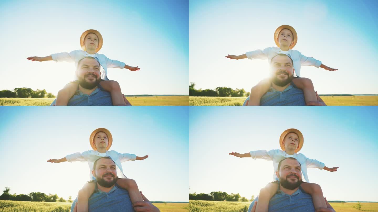 小男孩张开双臂，坐在爸爸的肩上，他在夕阳下走在麦田里。幸福的一家人一起漫步在大自然的夏日。农业。乡村