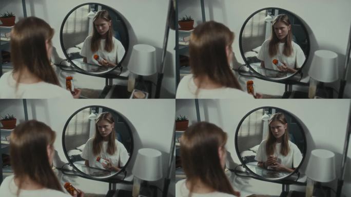 抑郁的女孩拿着药片照镜子