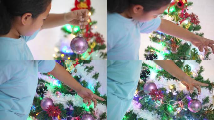 小女孩把圣诞球挂在树上。