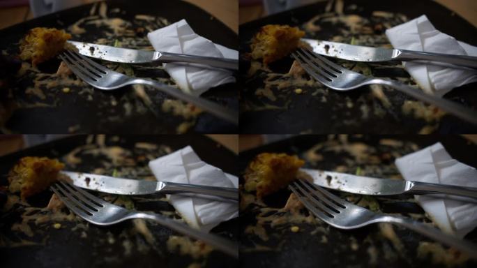 在餐馆吃完午饭后，桌子上的脏盘子，刀叉，白纸