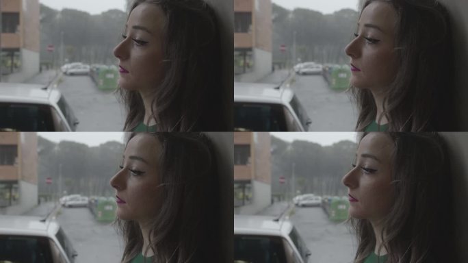 忧郁的年轻女子在下雨天站在窗前，遗憾地想起了她的前男友