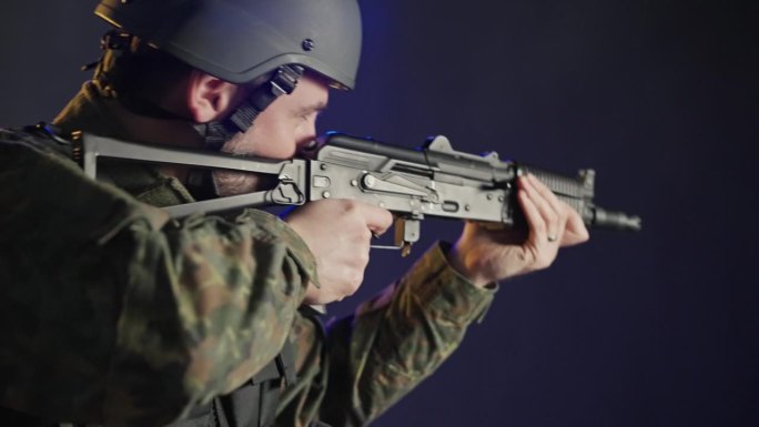 身穿军装、头戴头盔的士兵手持武器瞄准黑色背景的摄像机。