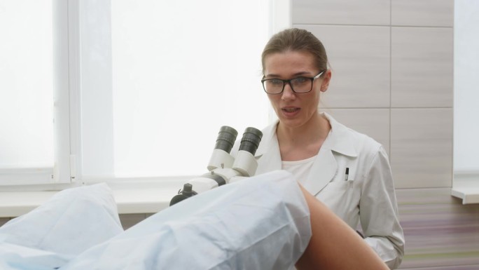 现代诊所的妇科。女妇科医生使用阴道镜，从病人身上进行检查。妇女在阴道镜检查过程中躺在妇科椅上。为怀孕