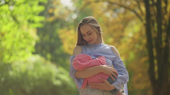 一位年轻妇女抱着一个婴儿，用牛奶喂他