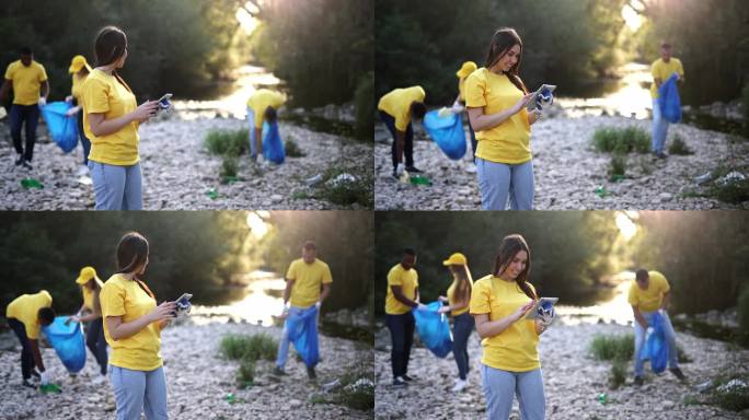 年轻的女志愿者在河岸上用写字板计划清扫