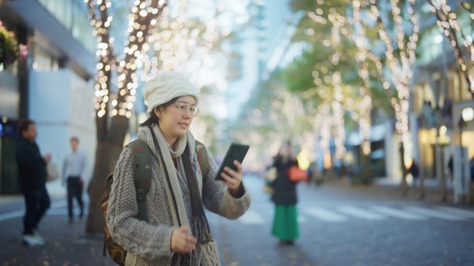 快乐的游客在圣诞节期间用智能手机在美丽的街道上拍照。