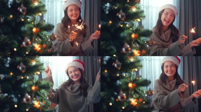 快乐的亚洲妇女手持圣诞彩灯，在装饰过的圣诞树、房屋装饰旁燃烧，准备在家里庆祝圣诞节和新年。