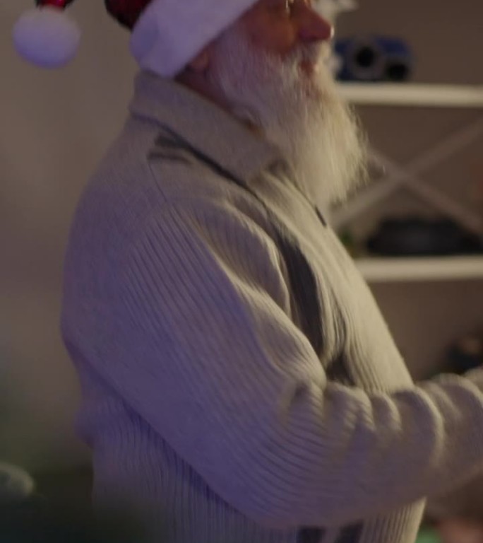 垂直视频，特写，一个留着胡子戴着圣诞帽的老人在跳舞。