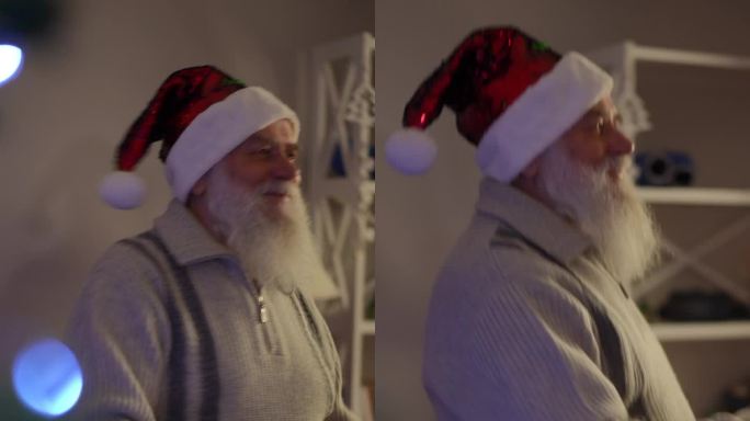垂直视频，特写，一个留着胡子戴着圣诞帽的老人在跳舞。