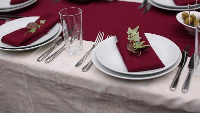 红色餐巾纸，白色盘子，常青藤装饰，优雅的节日宴会餐桌，精致的婚礼或宴会用餐设置，节日活动设计的趋势。