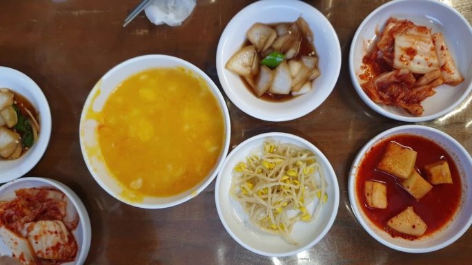 手吃韩国菜盘菜配菜和Hobakjuk南瓜粥顶视图手用筷子4k