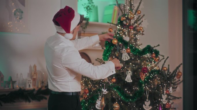 一名男子在家里用金箔和装饰品装饰圣诞树