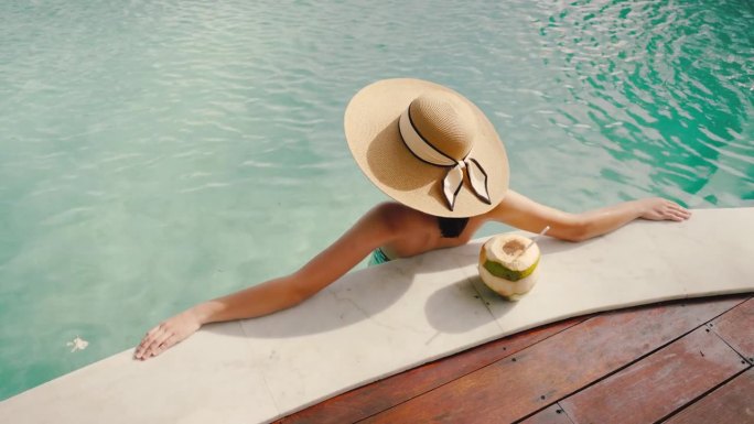 女子在游泳池放松日光浴，欣赏海景