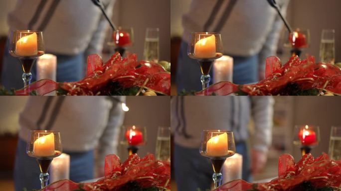 一个穿毛衣的男人点完桌上的蜡烛，跳起舞来，从桌上拿起一杯白起泡酒。