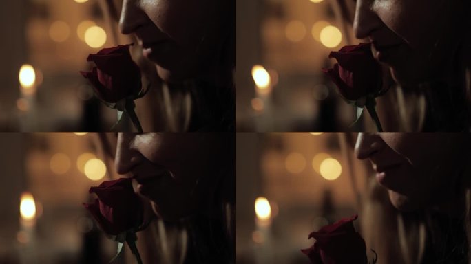 日期，情人节，周年纪念。女人的脸在浪漫的烛光下闻着红玫瑰花的特写