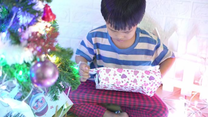 12月，小男孩在圣诞树旁拆礼物。