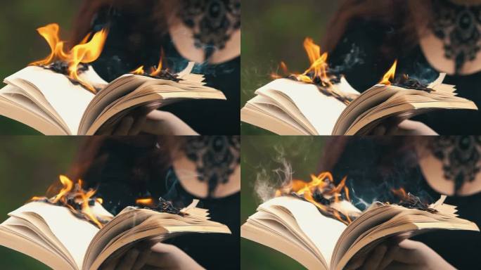年轻的哥特女人在森林里拿着一本燃烧的书