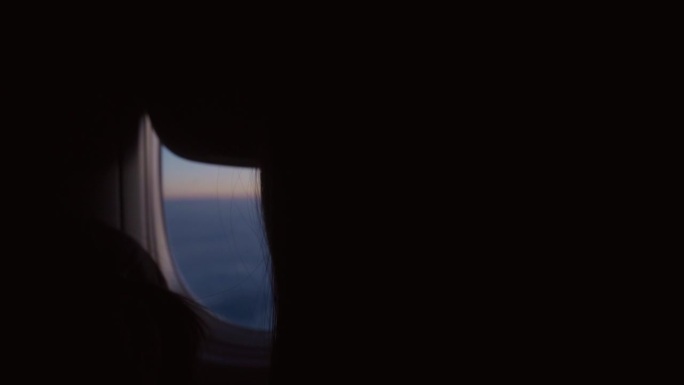在飞行中，一位女士打开飞机窗户，让光线射入机舱。