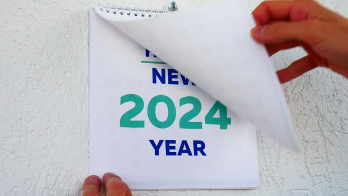 特写:男性的手撕下了2023年12月挂历的一页，紧接着撕下了新的2024年挂历的扉页