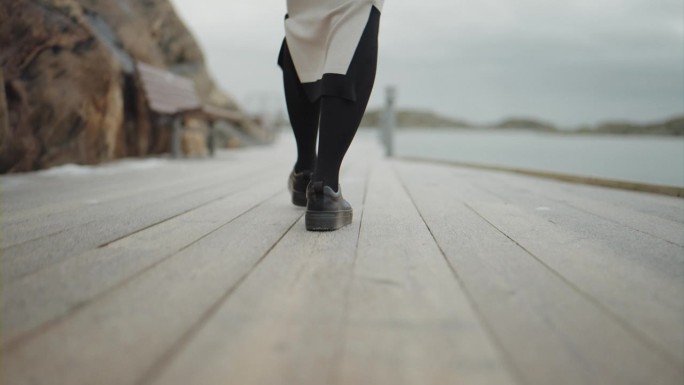 冬天沿着海岸走的女人，腿的特写，走在码头上