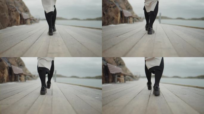 冬天沿着海岸走的女人，腿的特写，走在码头上