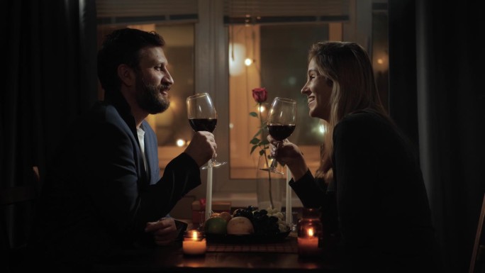 约会，情人节，结婚纪念日。烛光下的浪漫晚餐，男人和女人手拿酒杯坐在一起聊天，在浪漫的环境中聊天