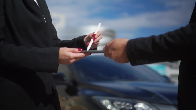 (特写)西装革履的女商人手签合同，给客户新车钥匙，为成功的汽车经销商握手。买、卖、租概念车。