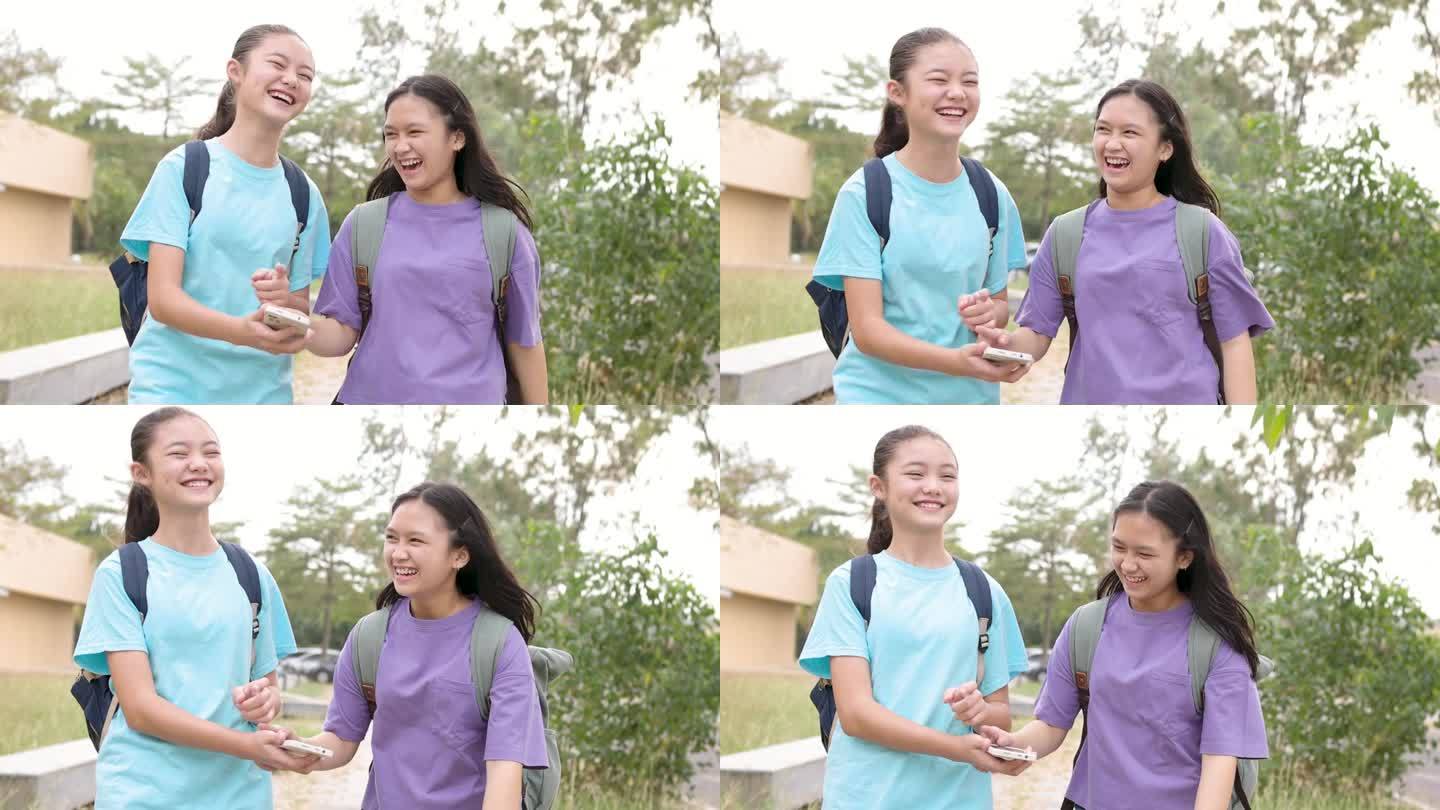 快乐的亚洲学生女孩在学校走路和使用智能手机