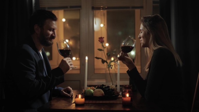 约会，情人节，干杯。男人和女人在家里或餐馆烛光晚餐，品尝葡萄酒和欢呼声