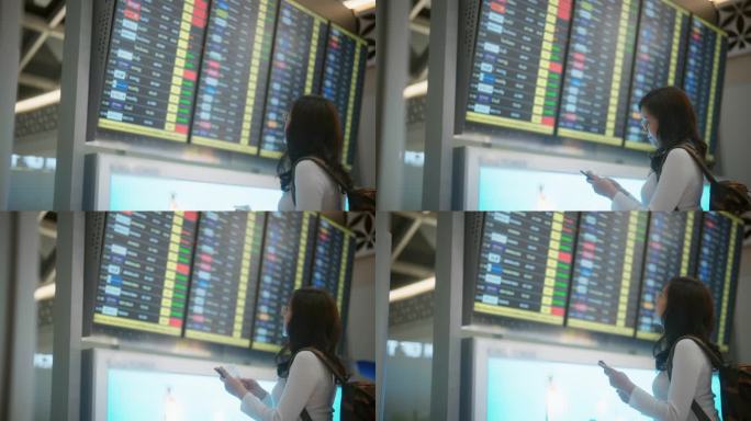 怀孕的亚洲女商务旅客在机场候机楼查看航班时刻表。