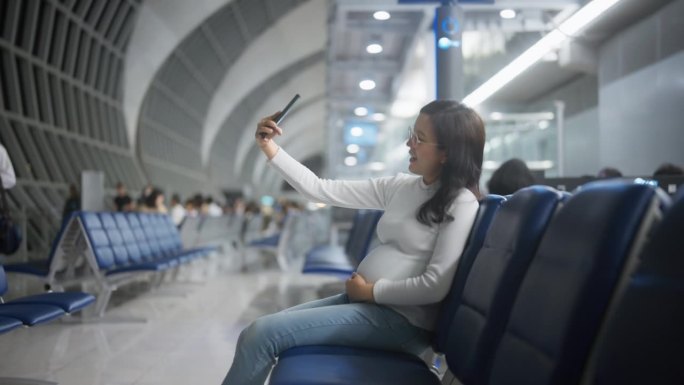 亚洲孕妇在机场与朋友用手机视频通话