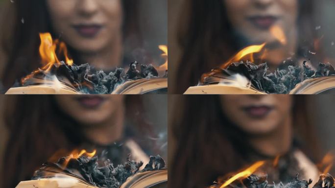 年轻的哥特女人在森林里拿着一本燃烧的书