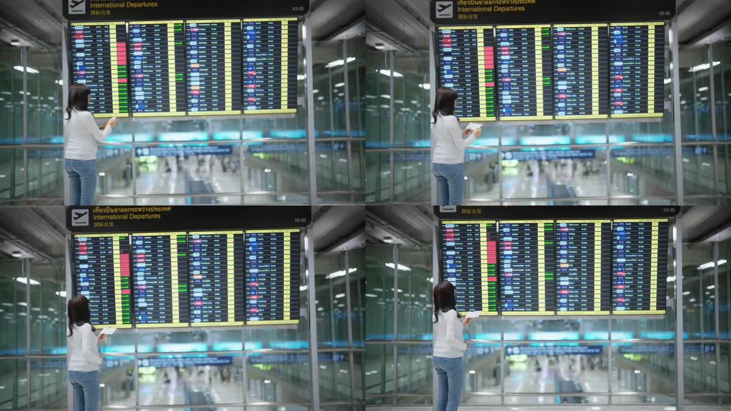 亚洲孕妇站在机场候机楼看时刻表