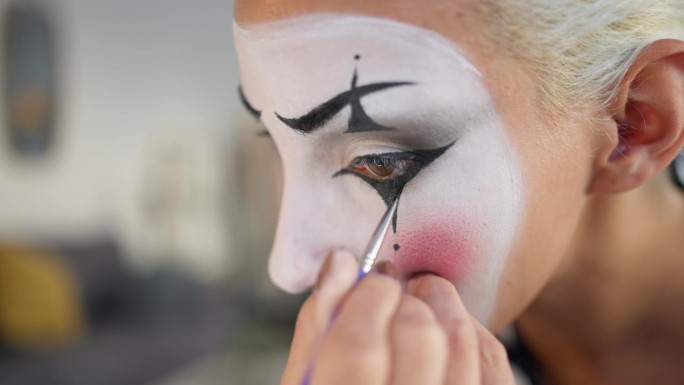 年轻女子，哑剧演员，在为哑剧表演做准备时，正在涂脸上的颜料。