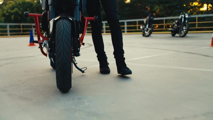 一个女孩在摩托车学校的训练场上驾驶摩托车的特写镜头。背景里有很多摩托车