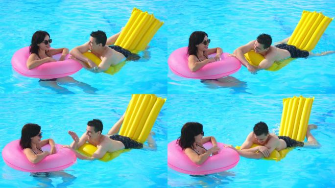 一对夫妇，一男一女，在泳池里放松，一起玩耍，享受炎热的夏日。