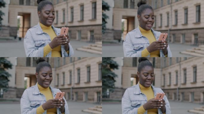 快乐的年轻非洲裔美国女士使用智能手机短信享受在线交流在街上