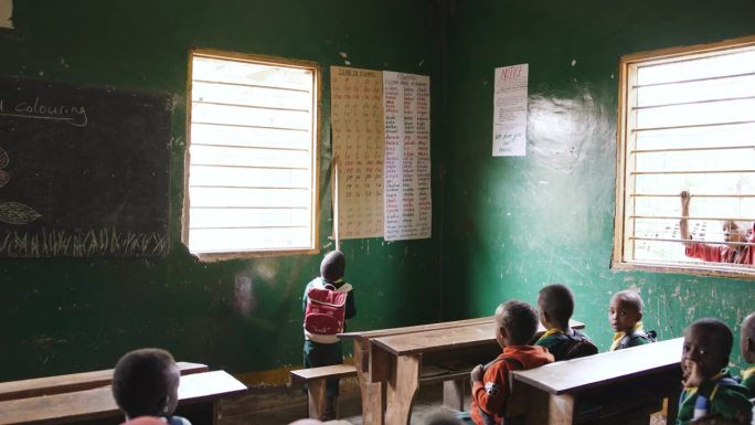 男孩在教室里指着图表的手持镜头。学生们在农村的学校学习。他们在一起学习。