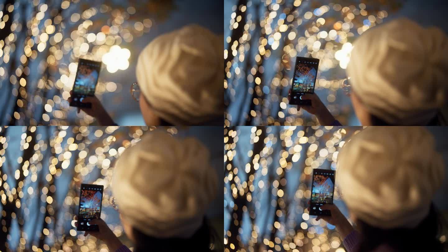 一名亚洲妇女用手机拍摄城市的圣诞灯